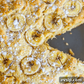 Apple banana bread topped with sliced bananas and dusted with powdered sugar.