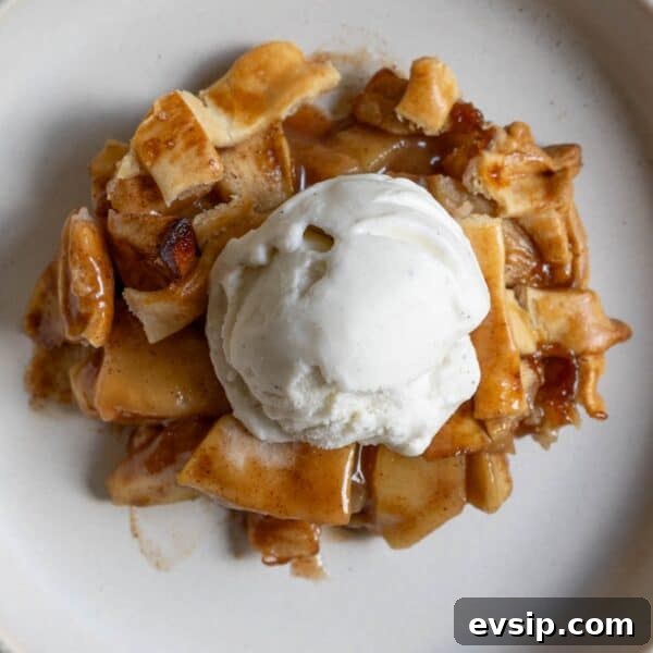 A slice of apple pie topped with vanilla ice cream.