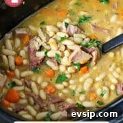 Ham and bean soup in a slow cooker with a ladle in it.