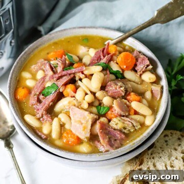 Bowl of ham and bean soup with a spoon in it.