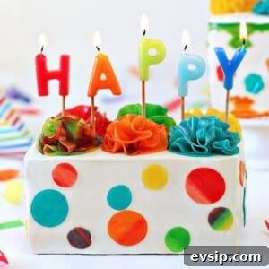 Piñata Cake Recipe with Video: Step-by-Step Guide 8 White rectangular cake with candy polka dots and lit birthday candles on top.