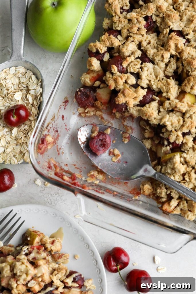 Apple Cherry Tahini Crumble Recipe — Rustic Fruit Dessert 12 Apple cherry tahini crumble served in glass baking dish with spoon and oats