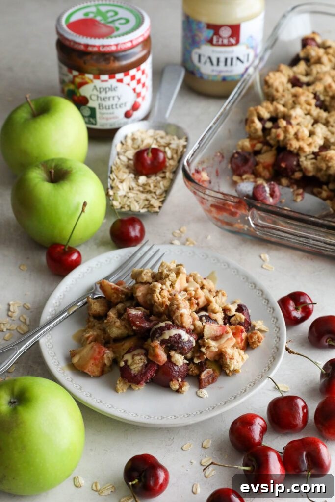 Apple Cherry Tahini Crumble Recipe — Rustic Fruit Dessert 11 Apple cherry tahini crumble served on plate surrounded by cherries and apple