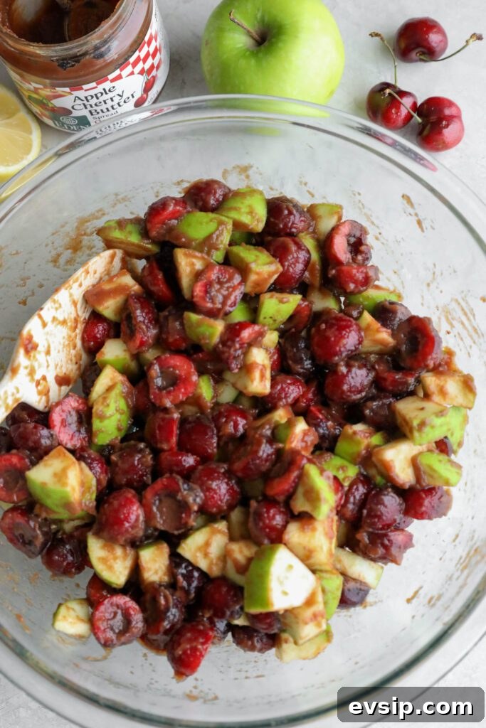 Apple Cherry Tahini Crumble Recipe — Rustic Fruit Dessert 6 apples and cherries mixed with apple butter in glass bowl