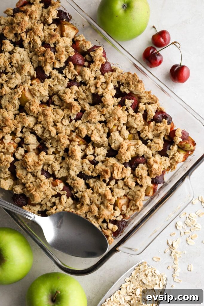 Apple Cherry Tahini Crumble Recipe — Rustic Fruit Dessert 10 Apple Cherry Tahini Crumble baked in glass dish with a spoon surrounded by cherries and apples
