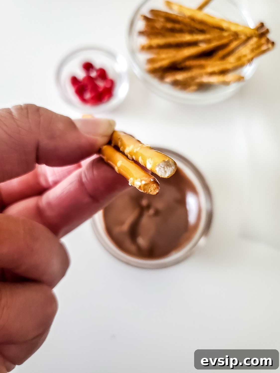 pretzel rods being dipped in chocolate