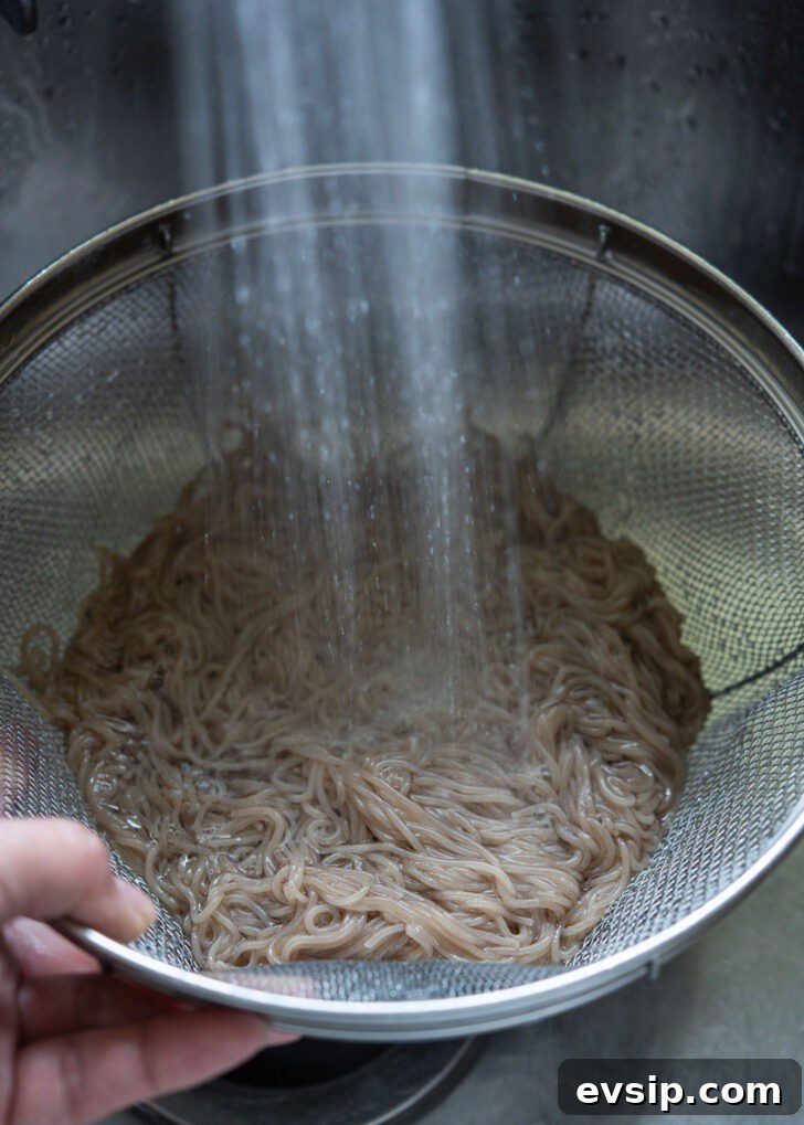 Cooked naengmyeon noodles rinsed under cold water to cool and improve texture.