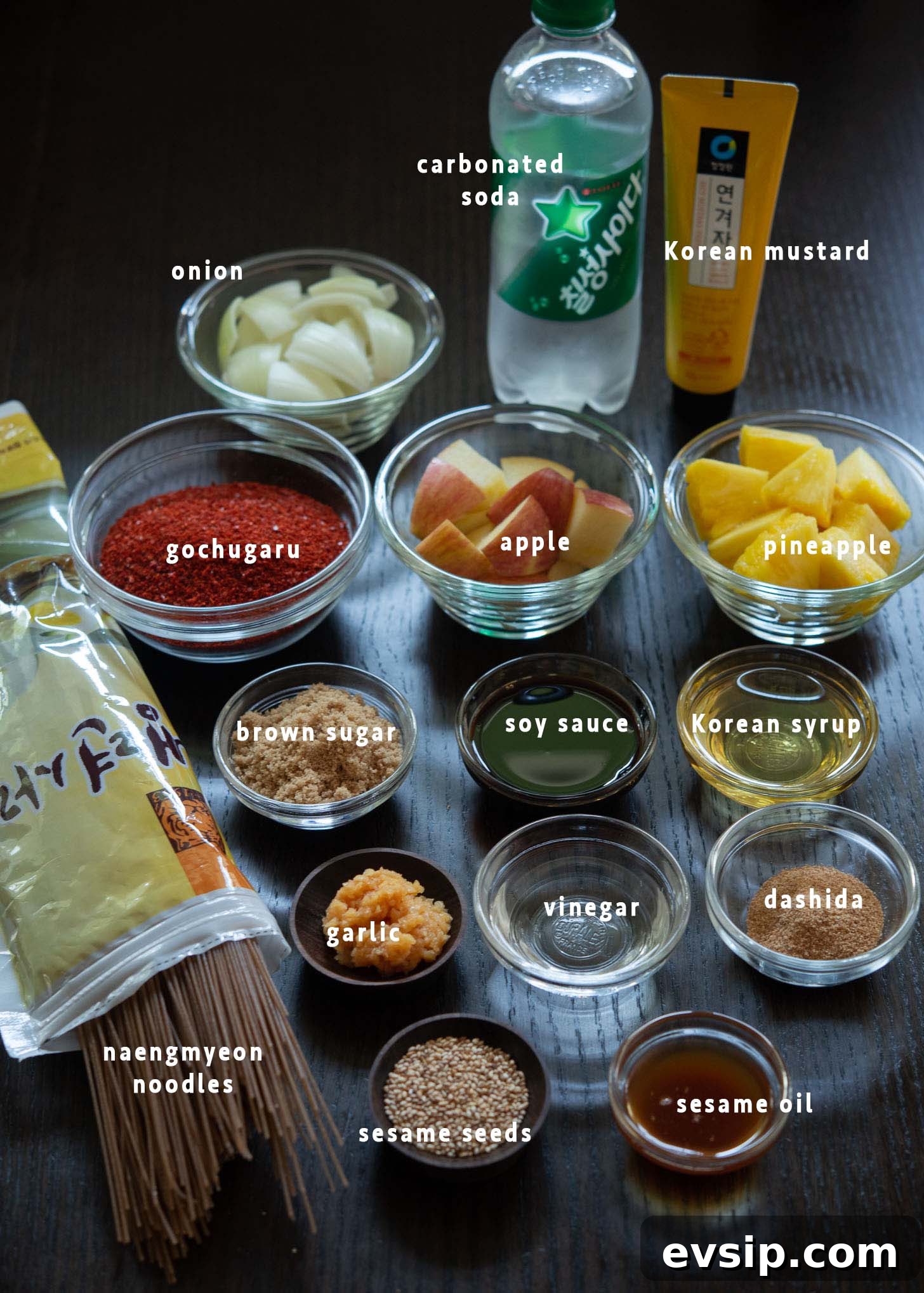 Ingredients prepared for making bibim naengmyeon, including chili flakes, soy sauce, and fresh produce.