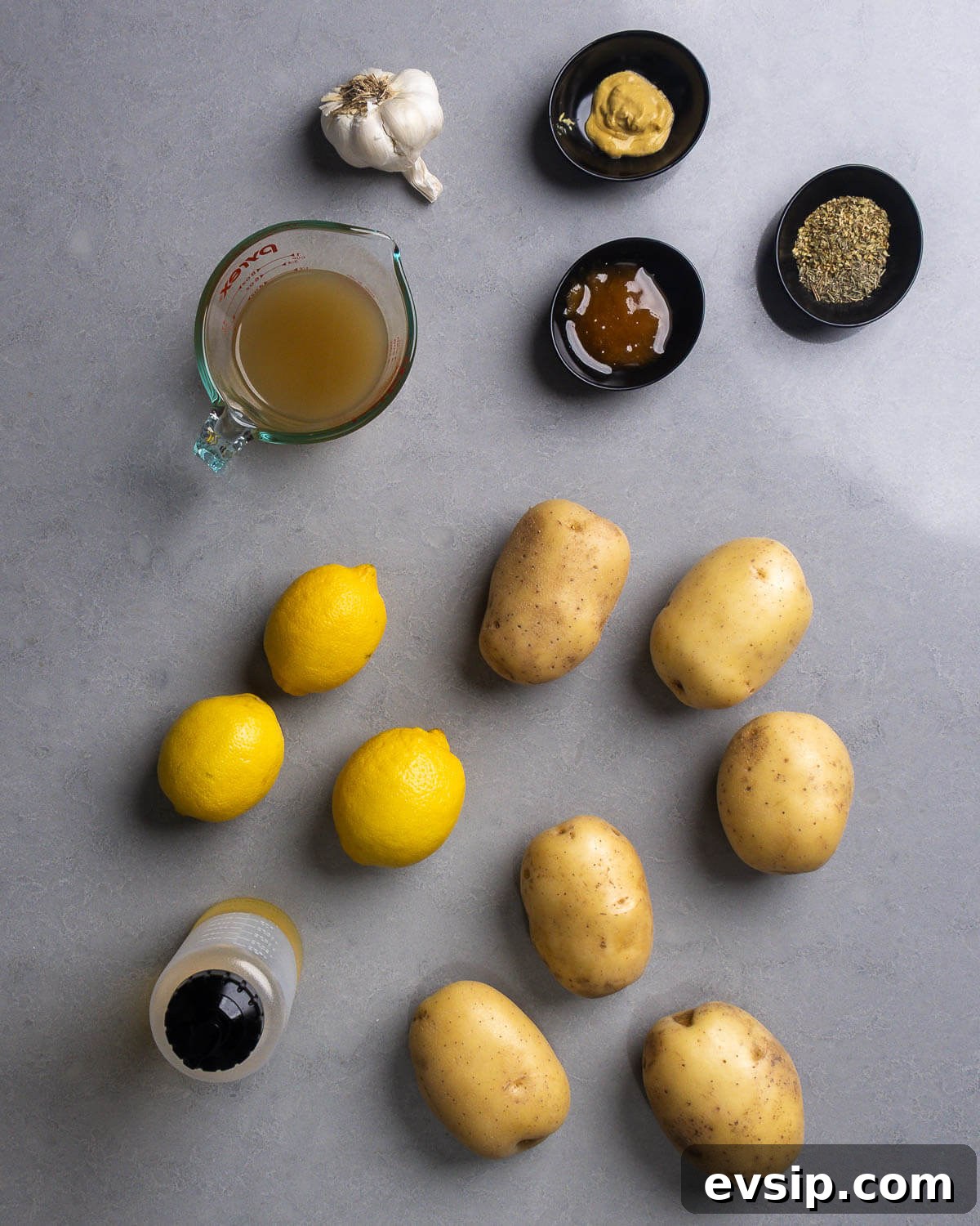 Lemon Oregano Roasted Greek Potatoes 3 Ingredients shown: garlic, chicken stock, honey, Dijon mustard, oregano, lemons, potatoes, and olive oil.