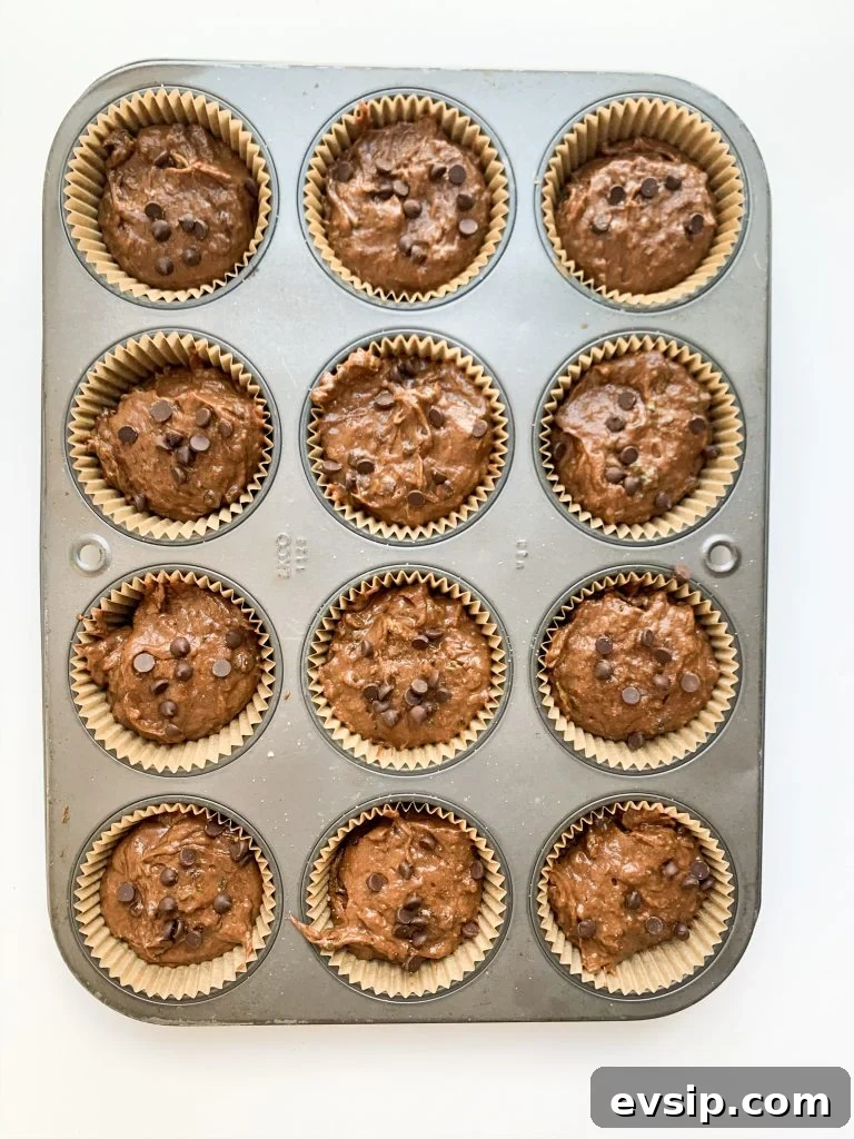 a muffin tin of chocolate zucchini muffin batter before baking