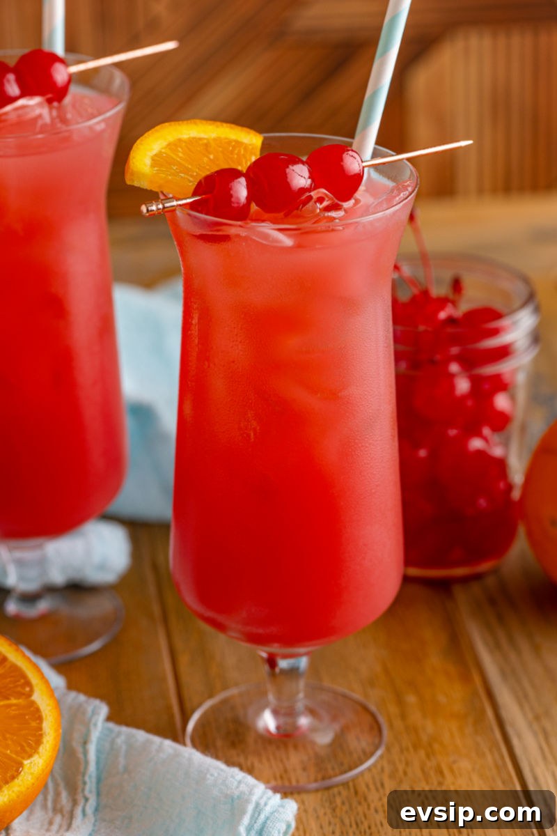 sex on the beach with a straw, orange, and cherries for garnish