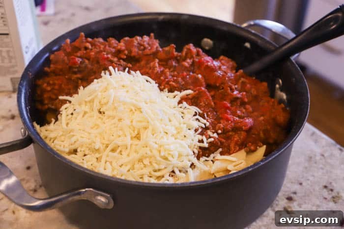 adding sauce and cheese to the pasta