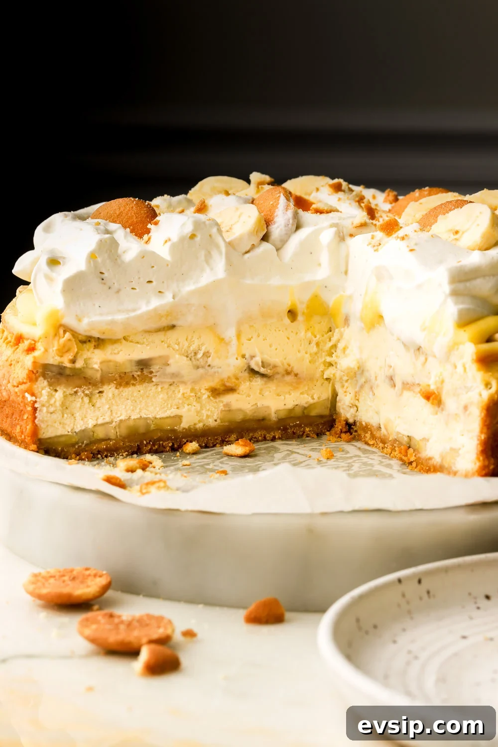 Banana Pudding Cheesecake Recipe with Creamy Layered Filling 27 Banana pudding cheesecake sliced into revealing layers of cheesecake, banana slices, vanilla pudding and whipped cream
