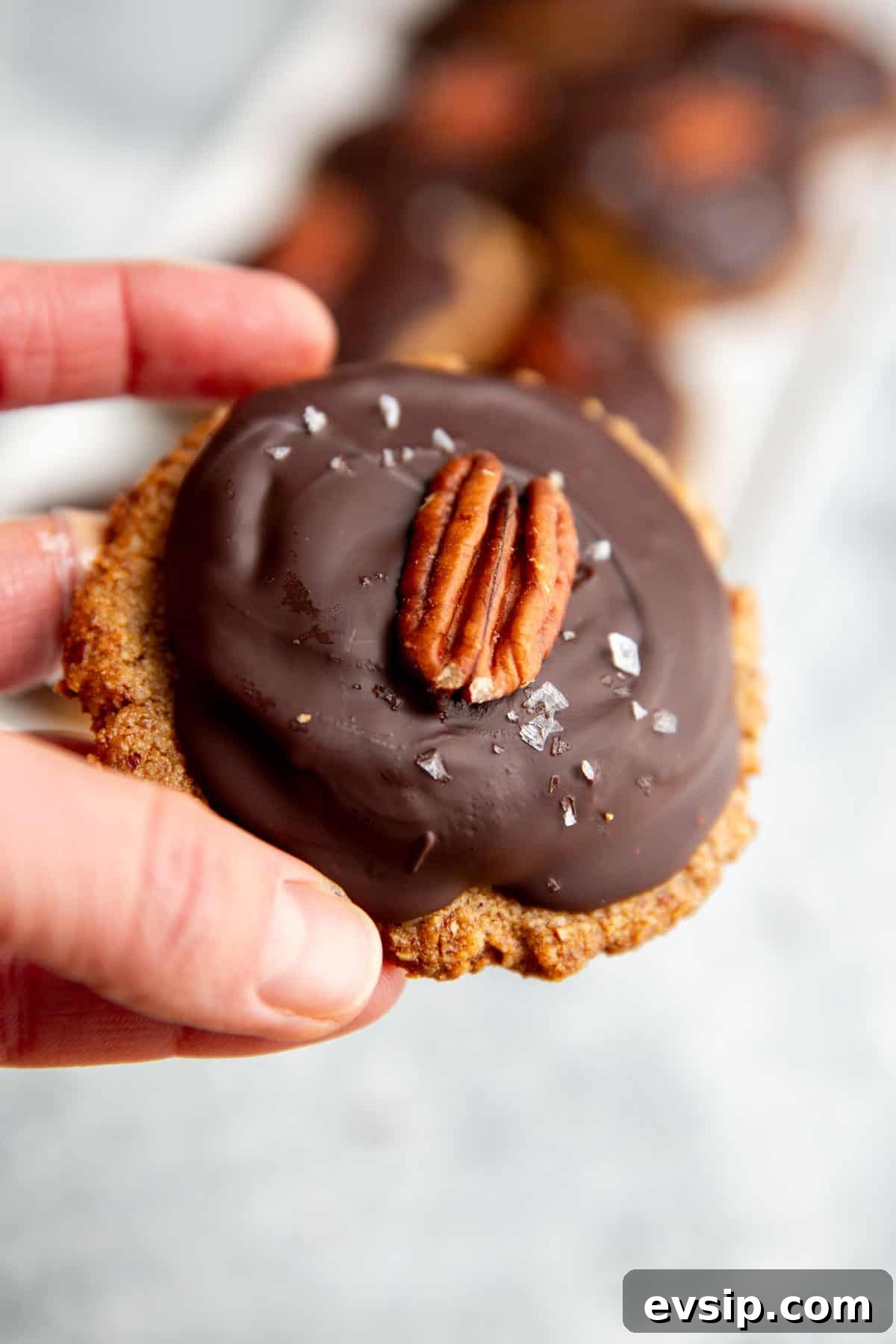 a hand holding a vegan turtle to show the various layers of the cookies