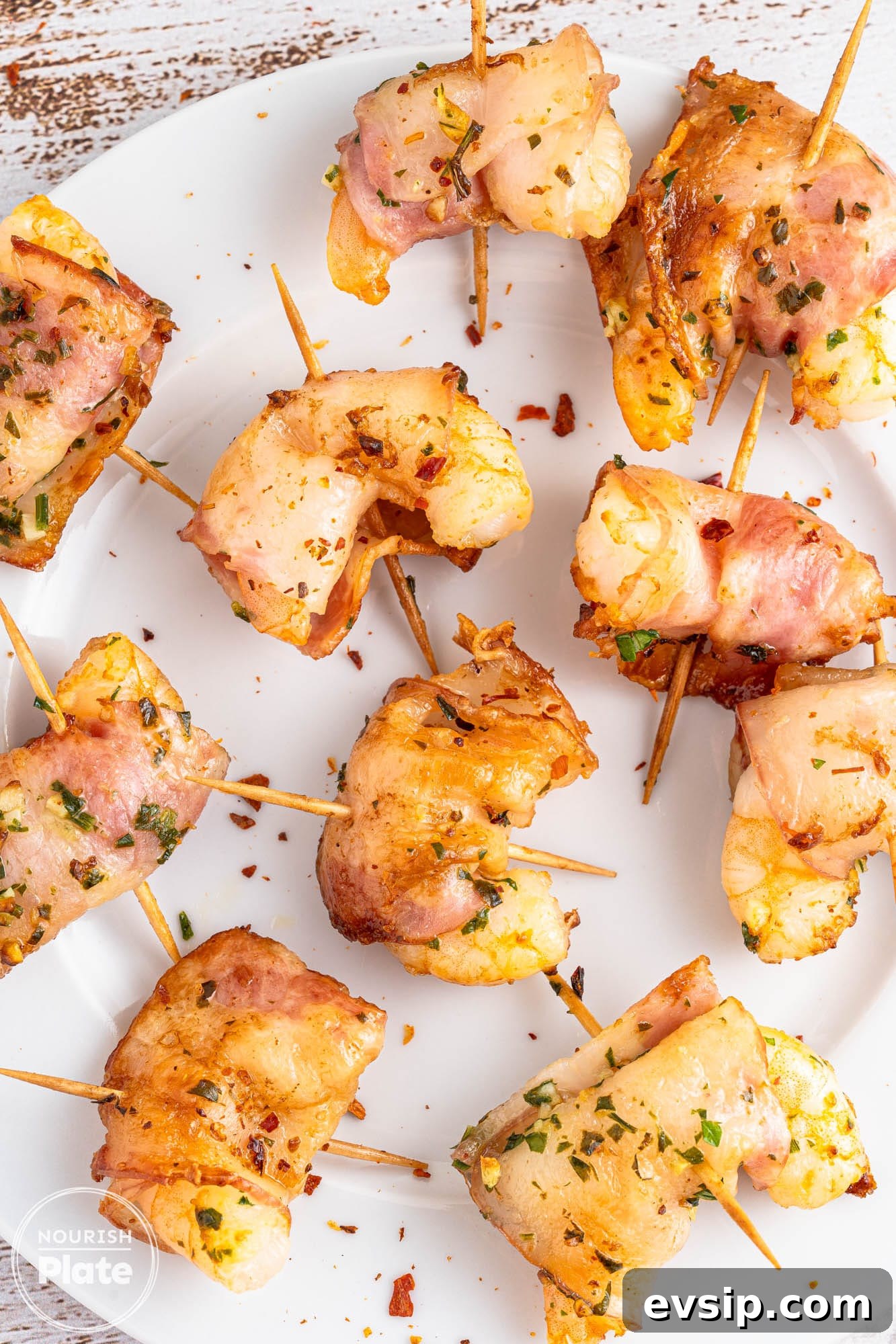 Overhead shot of bacon wrapped shrimp on a white plate