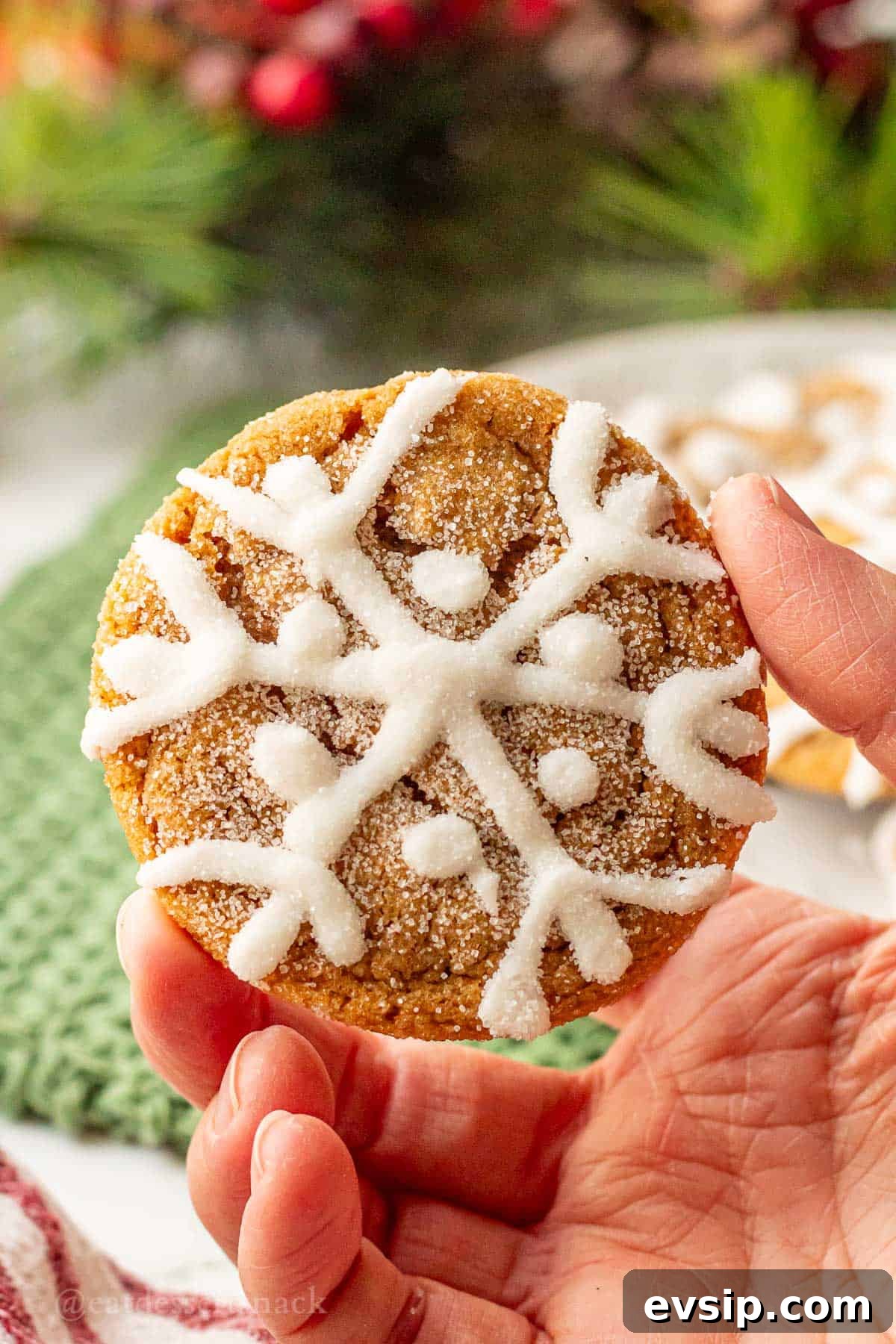 Hand holding baked iced ginger cookie.