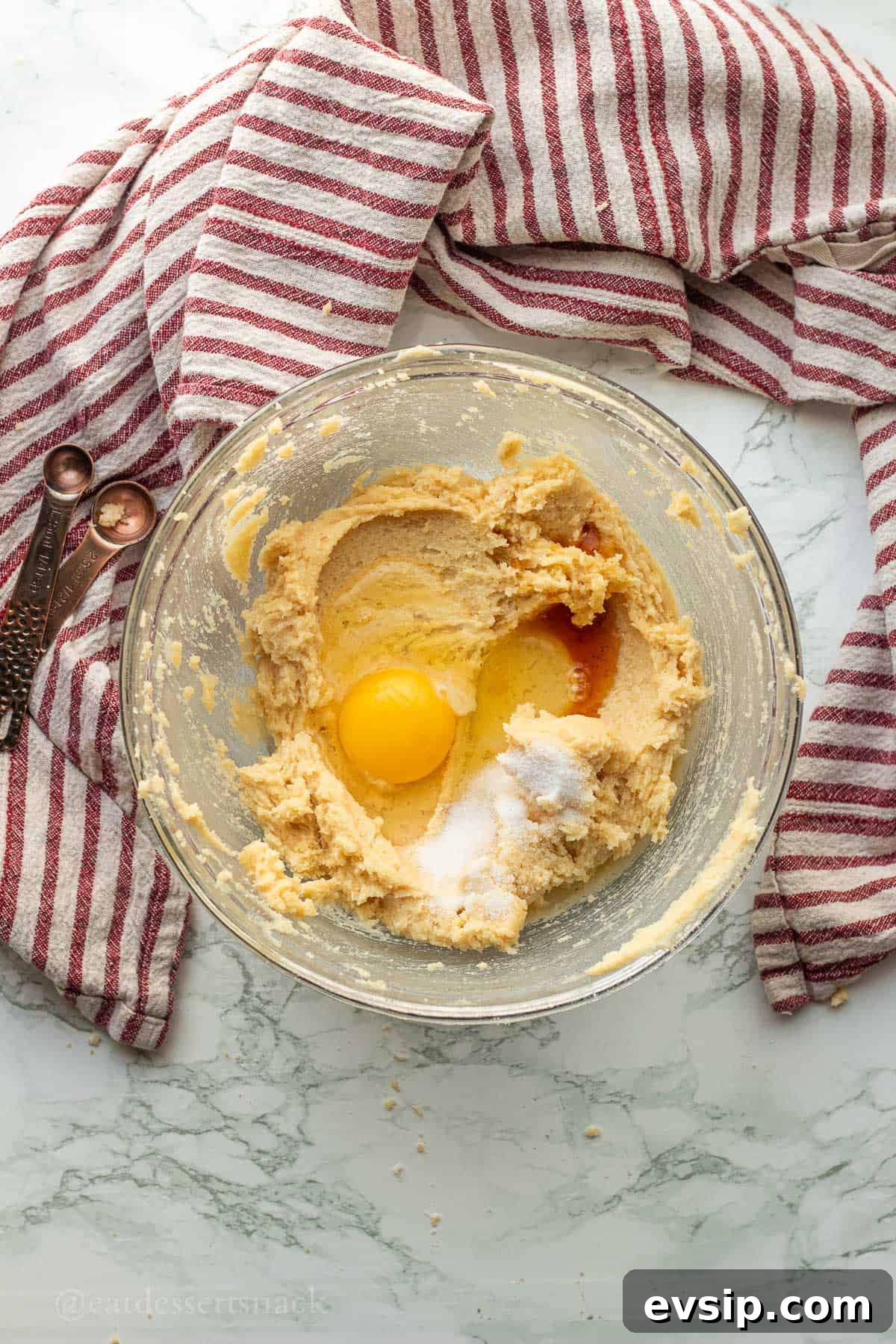 Egg, vanilla, and salt in glass bowl with creamed butter and sugar.