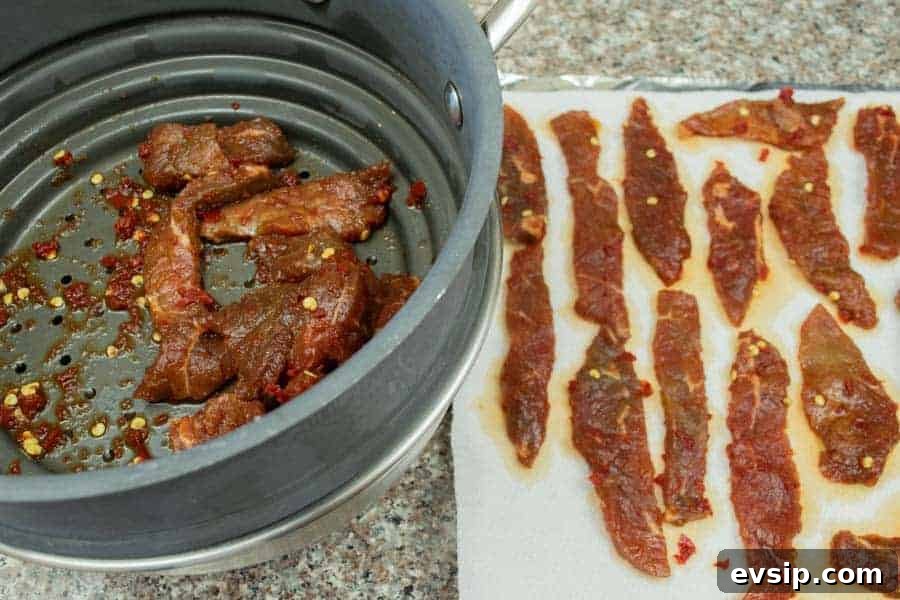Patting dry jerky strips on paper towels