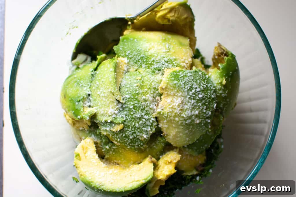 A glass bowl filled with scoops of avocado and sprinkled with salt. 