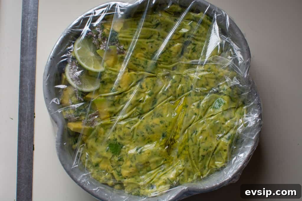 A bowl covered with plastic wrap sitting on a white counter. 