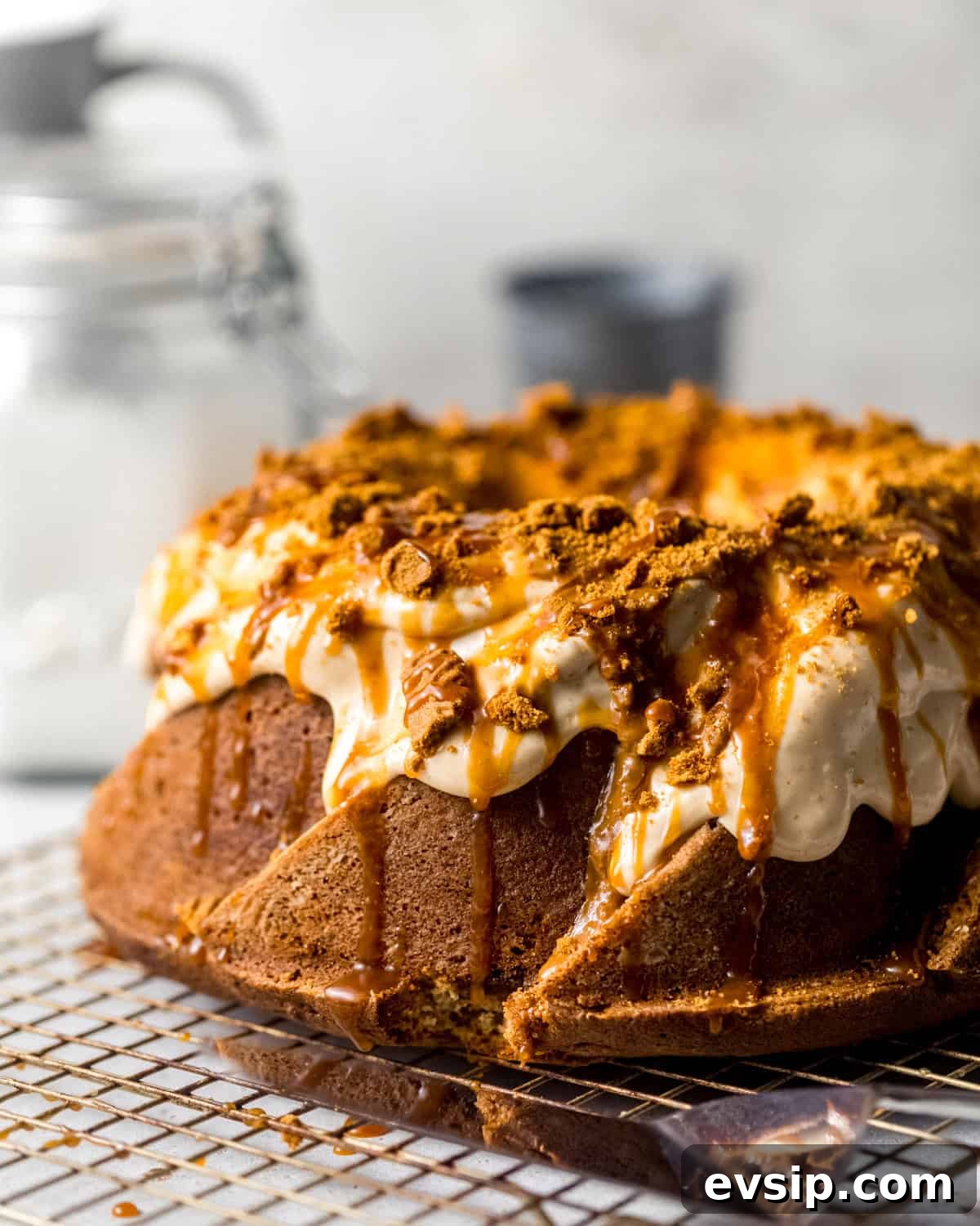 biscoff pound cake on a wire rack with glaze, caramel, and crushed cookies on top.