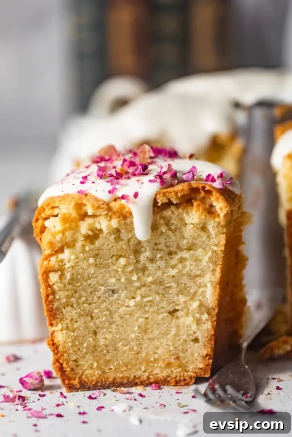 a slice of cream cheese pound cake on a white surface with rose petals on top.
