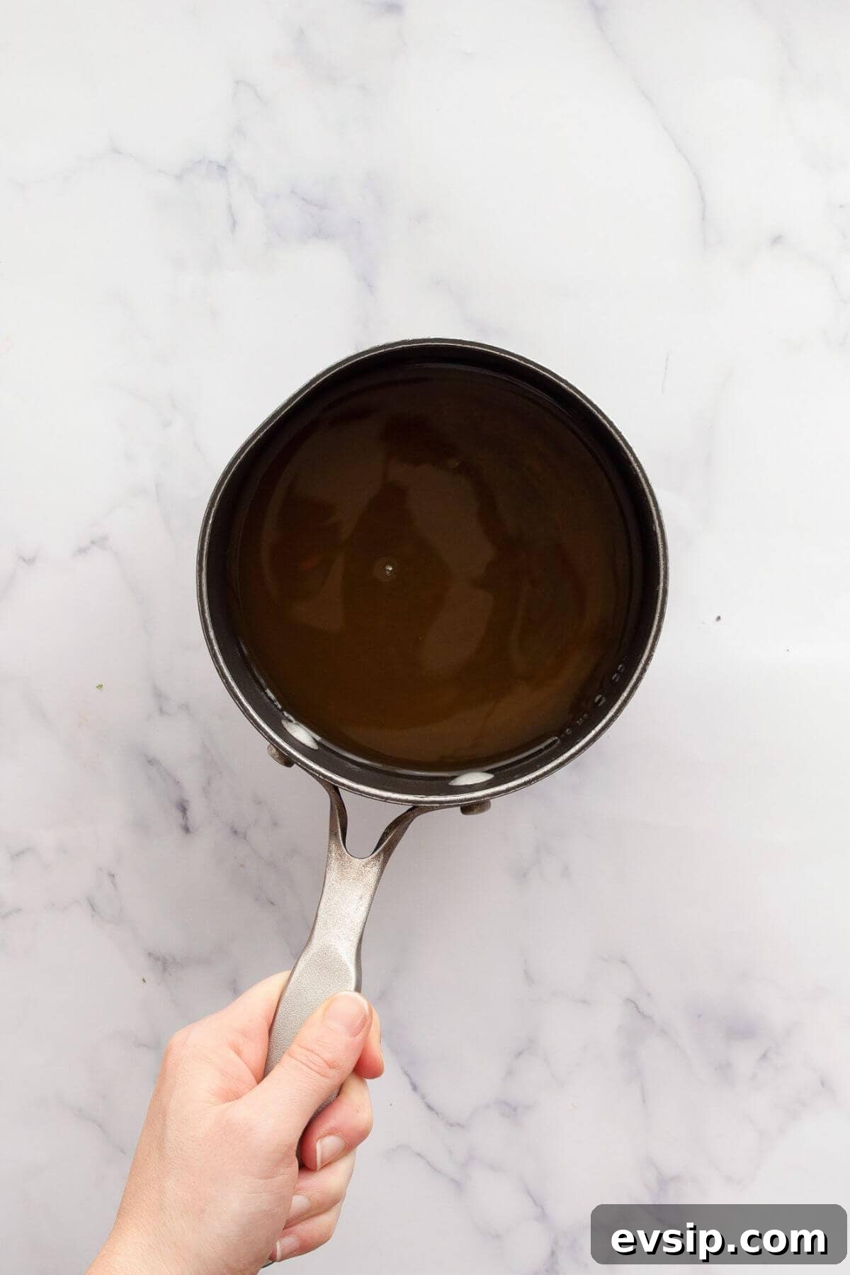 Dissolving honey in warm water in a saucepan to make lemonade popsicles.