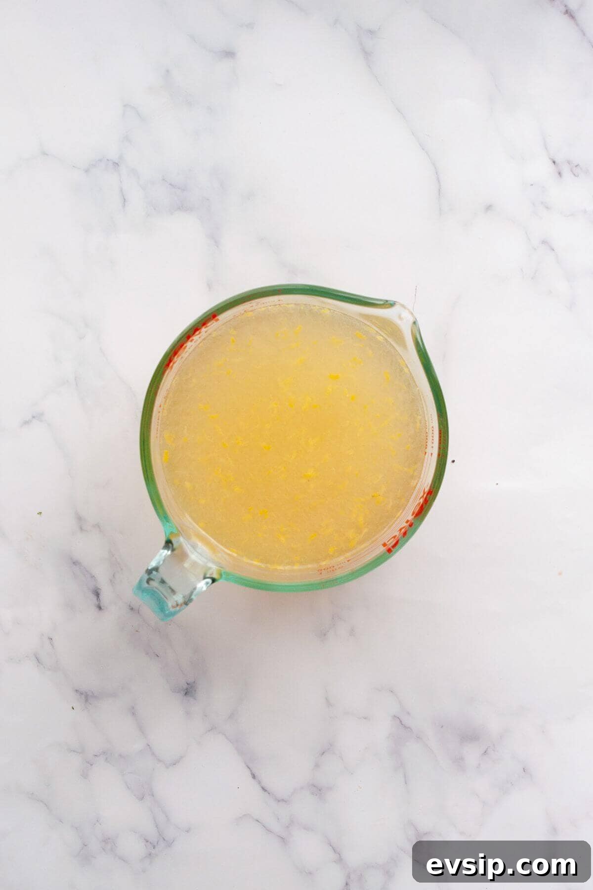 Mixing fresh lemon juice and zest with honey water for homemade lemonade popsicles.