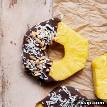 No-bake, healthy chocolate covered pineapple ring with coconut flakes.