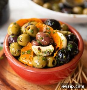 Marinated Olives close up side shot of marinated olives in small brown pot next to toothpicks