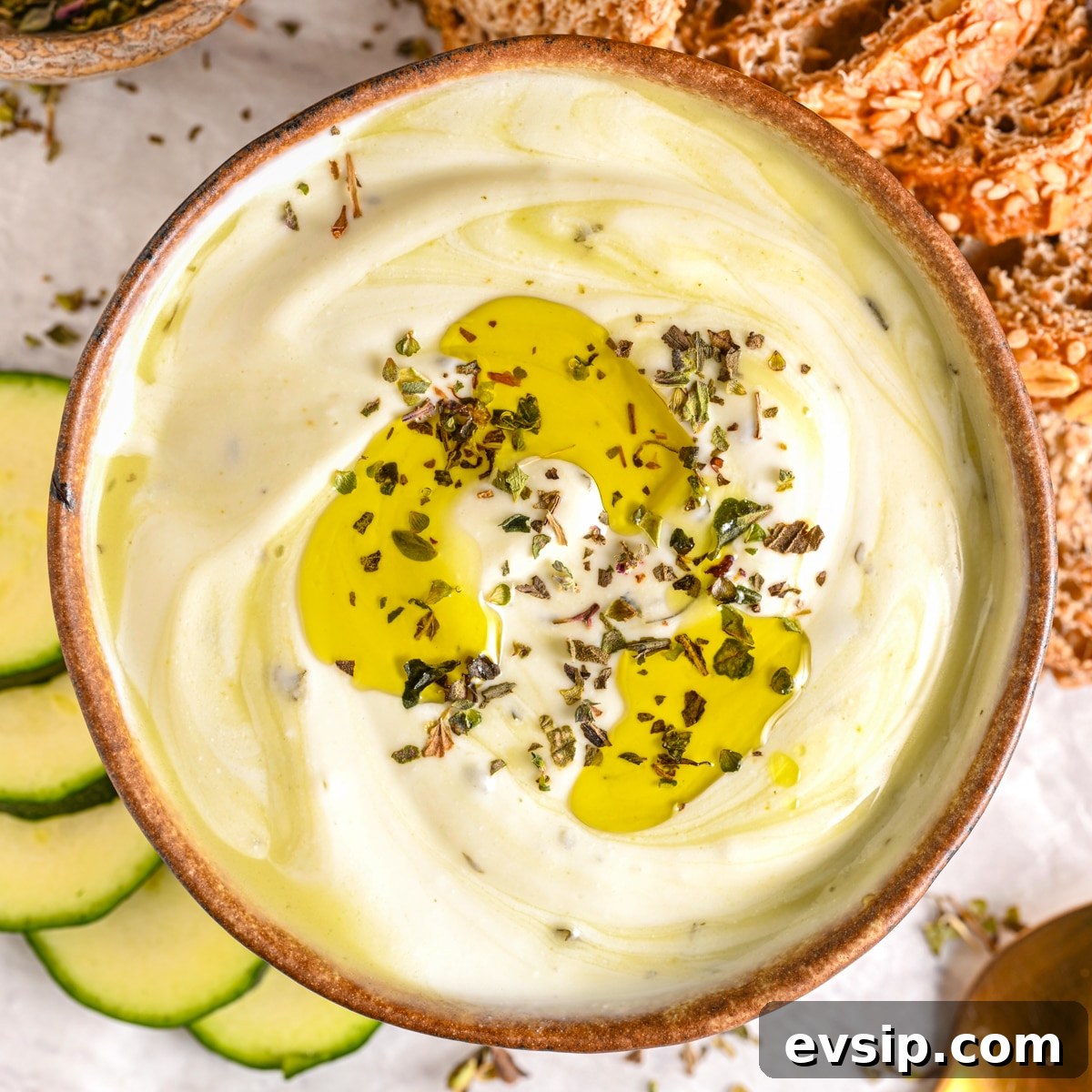 15 Delicious Cottage Cheese Recipes for Every Meal 17 Top-view of a rich and creamy cottage cheese dip, served with herbs and a drizzle of extra virgin olive oil on top.