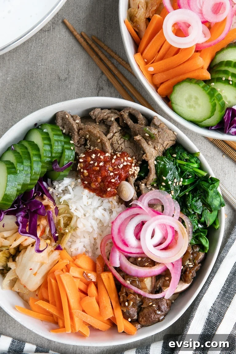 Korean Beef Bibimbap Recipe: Authentic Mixed Rice Bowl 4 bibimbap topped with bulgogi, cooked spinach, kimchi, carrots, cucumber, sauteed mushrooms and pickled red onion.