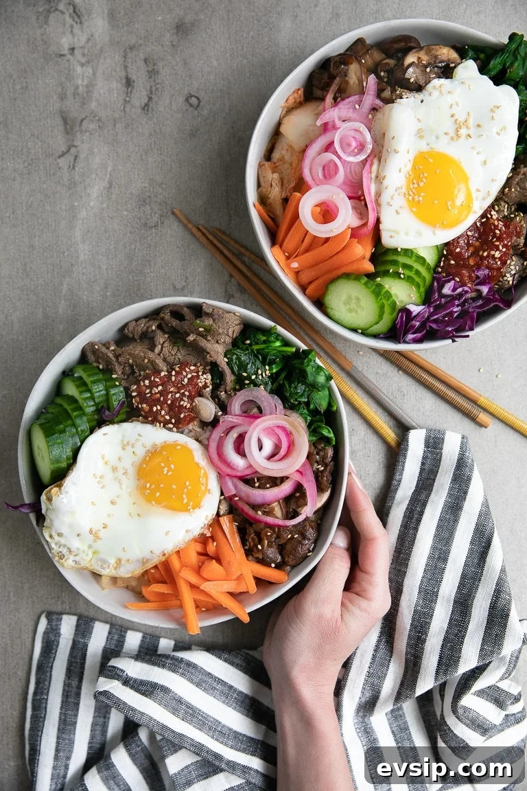 Korean Beef Bibimbap Recipe: Authentic Mixed Rice Bowl 5 bibimbap topped with korean beef, fresh vegetables, korean chili paste, sauteed vegetables, and fried egg.
