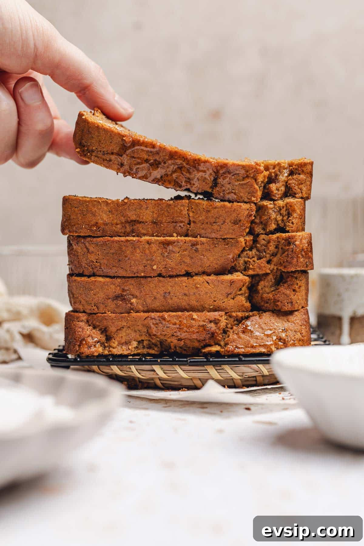 hand laying a piece of banana bread on a stack of banana bread slices. 