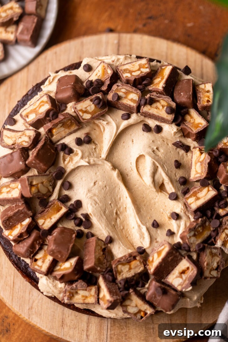 Decadent Snickers Dessert Cake Recipe for Chocolate Lovers 8 Decorated cake on a wood board.