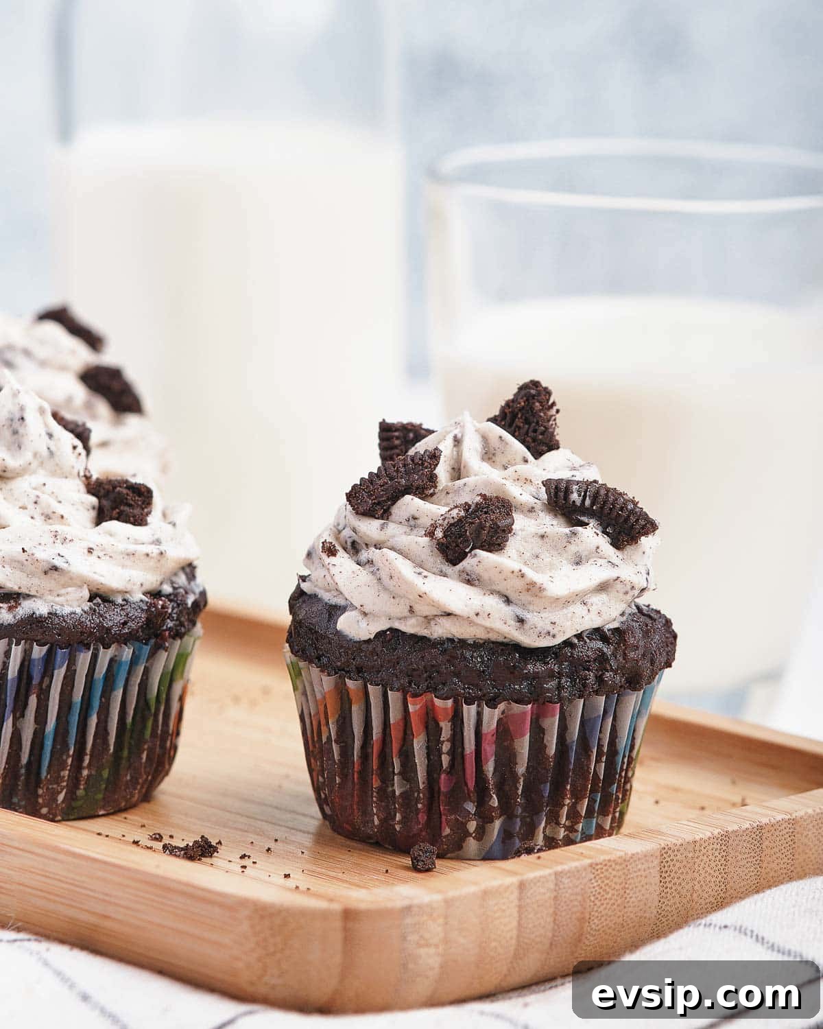 Chocolate cupcakes on wooden board with Oreo frosting and broken cookies on top.