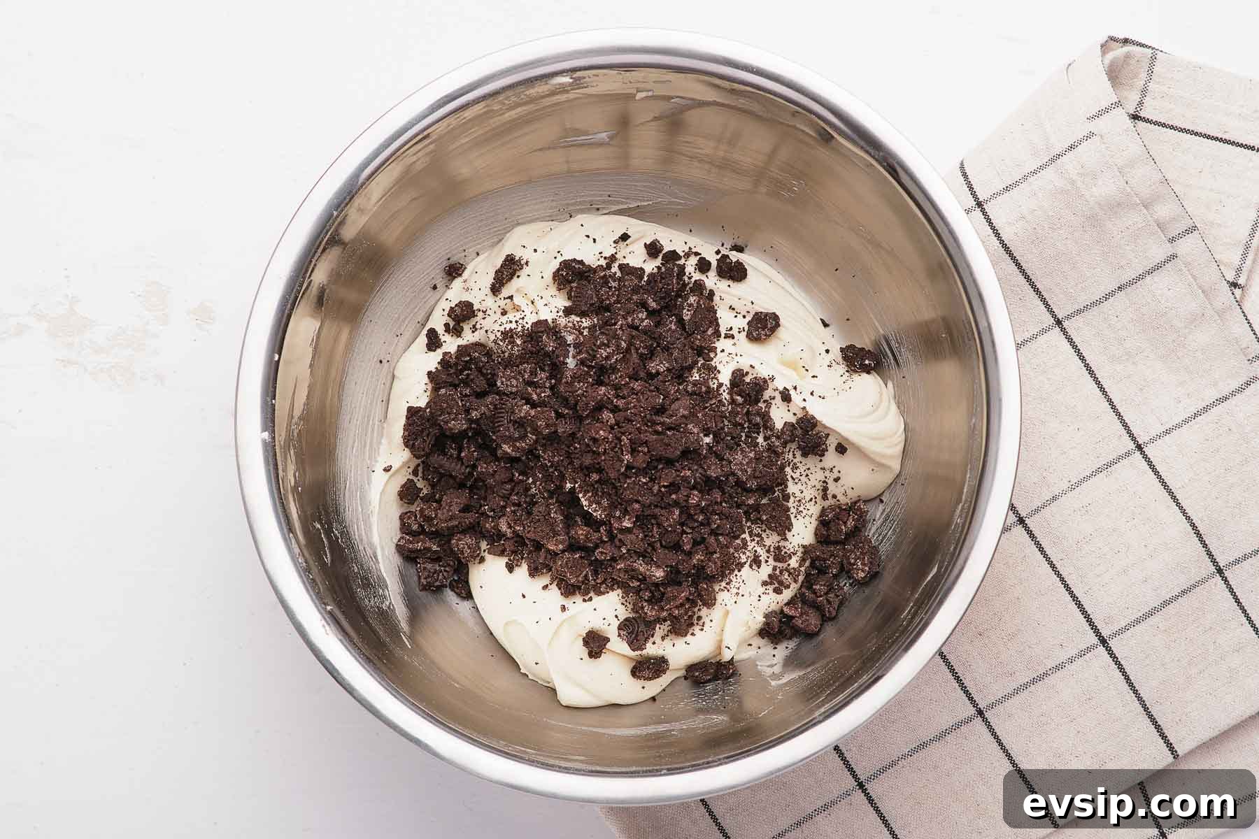 Crushed cookies on top of white frosting in bowl.