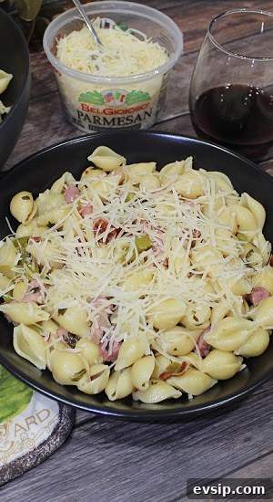 Plate of pasta topped with Parmesan cheese, a glass of wine.