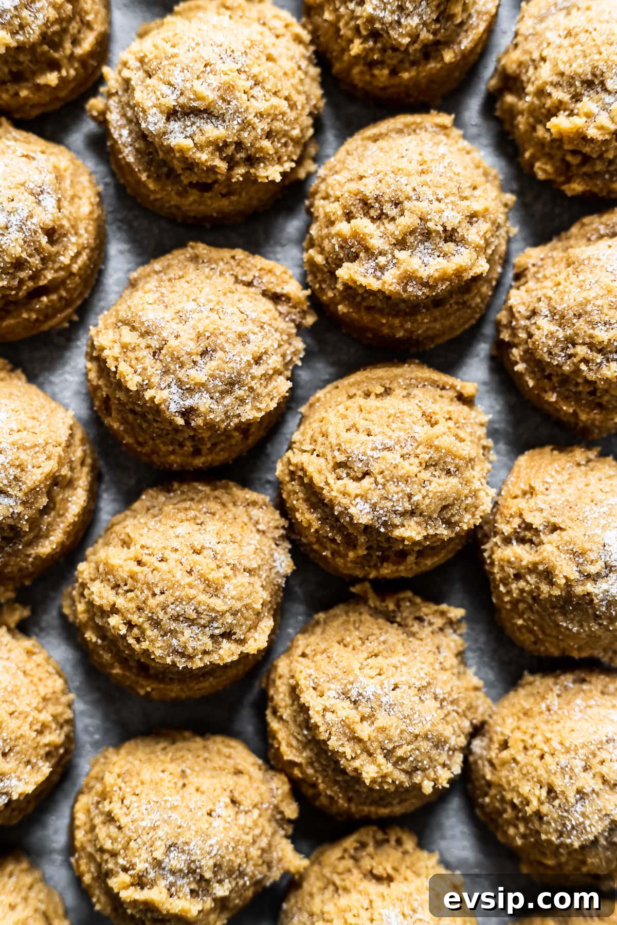 Scoops of cookie dough sprinkled with granulated sugar on a parchment lined baking sheet.