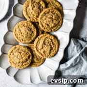 Peanut butter cookies on a fluted white ceramic serving plate. The plate rests on a white stone surface with a light blue linen napkin nearby.