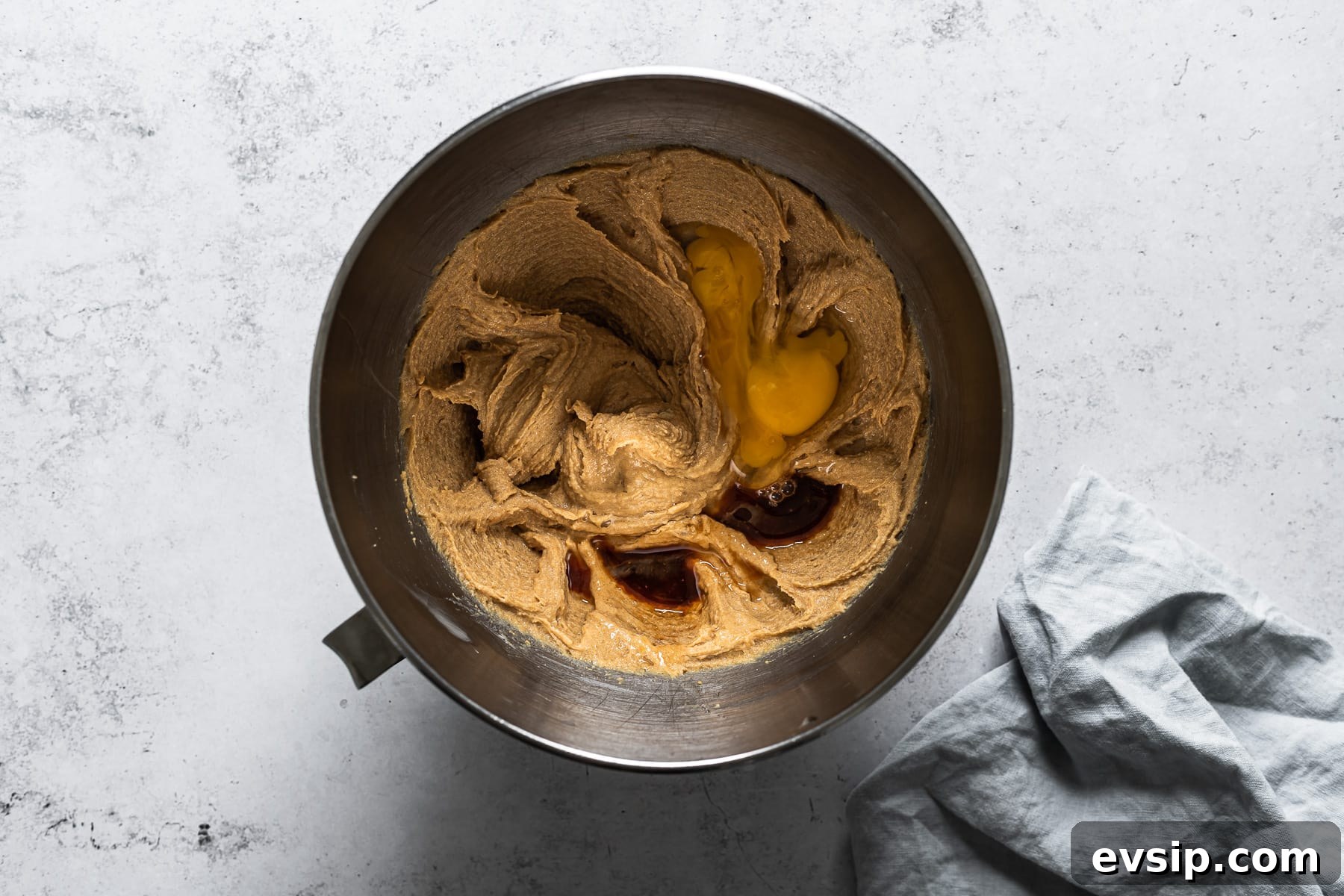 Process photo of a bowl of cookie dough with eggs and vanilla added.