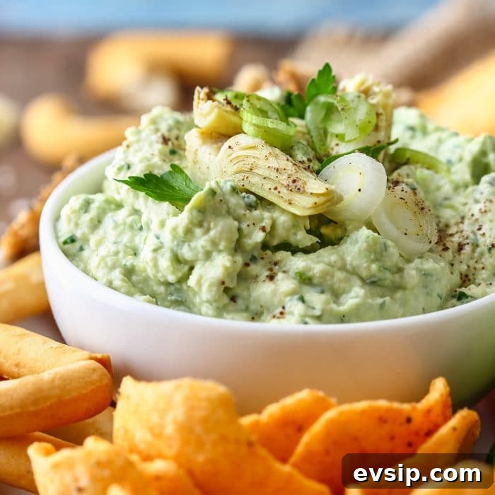 Green Artichoke Heart Dip on the white bowl with snacks