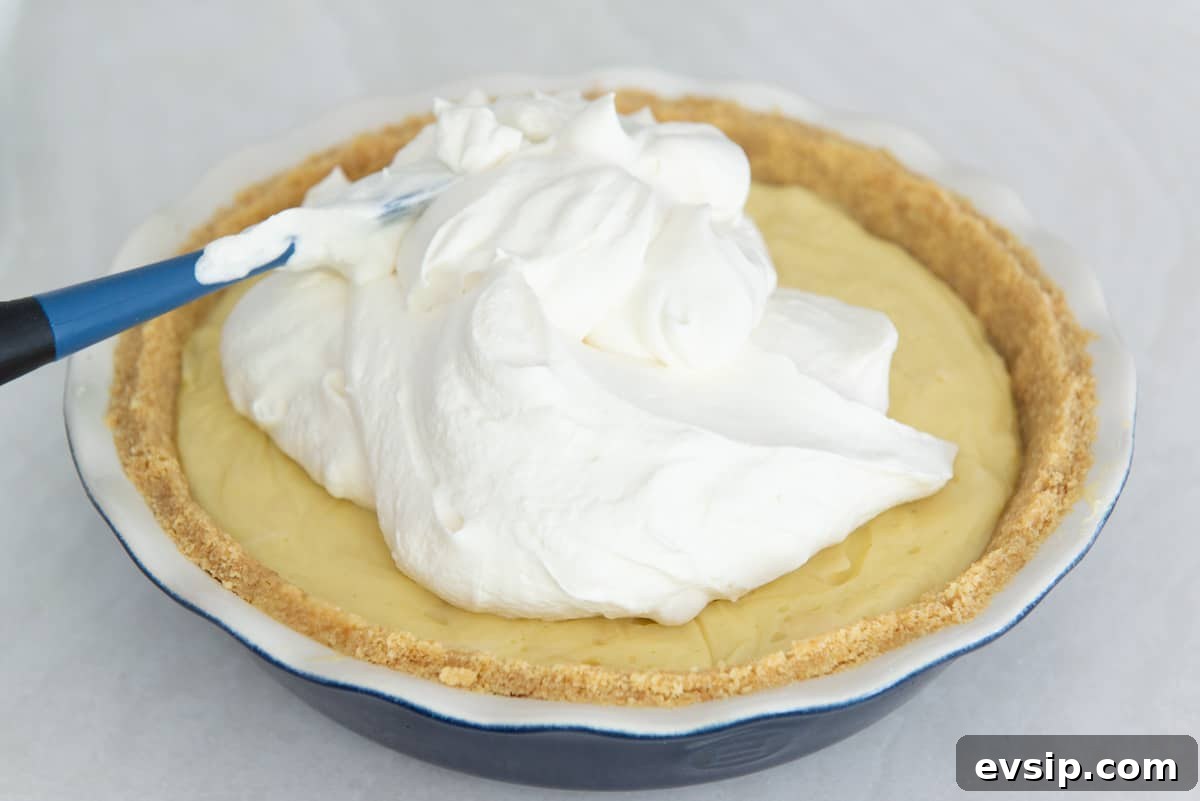 Classic Coconut Cream Pie Recipe: Silky, Homemade Dessert 14 A big dollop of whipped cream on top of the filling with a spatula