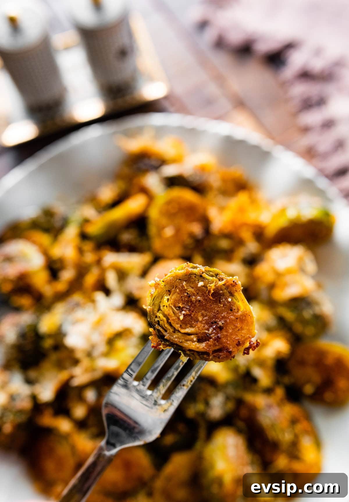 Parmesan Brussels Sprouts Recipe on a serving platter with serving utensils ready to serve. Close up of the final dish. Fork holding up the sprouts.