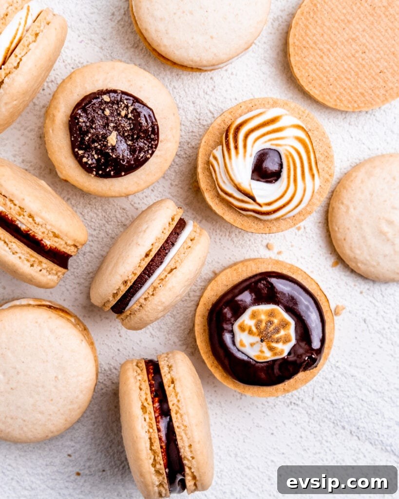 S'mores macarons laying on their side and graham cracker macaron shells with chocolate ganache and marshmallow cream piped on them