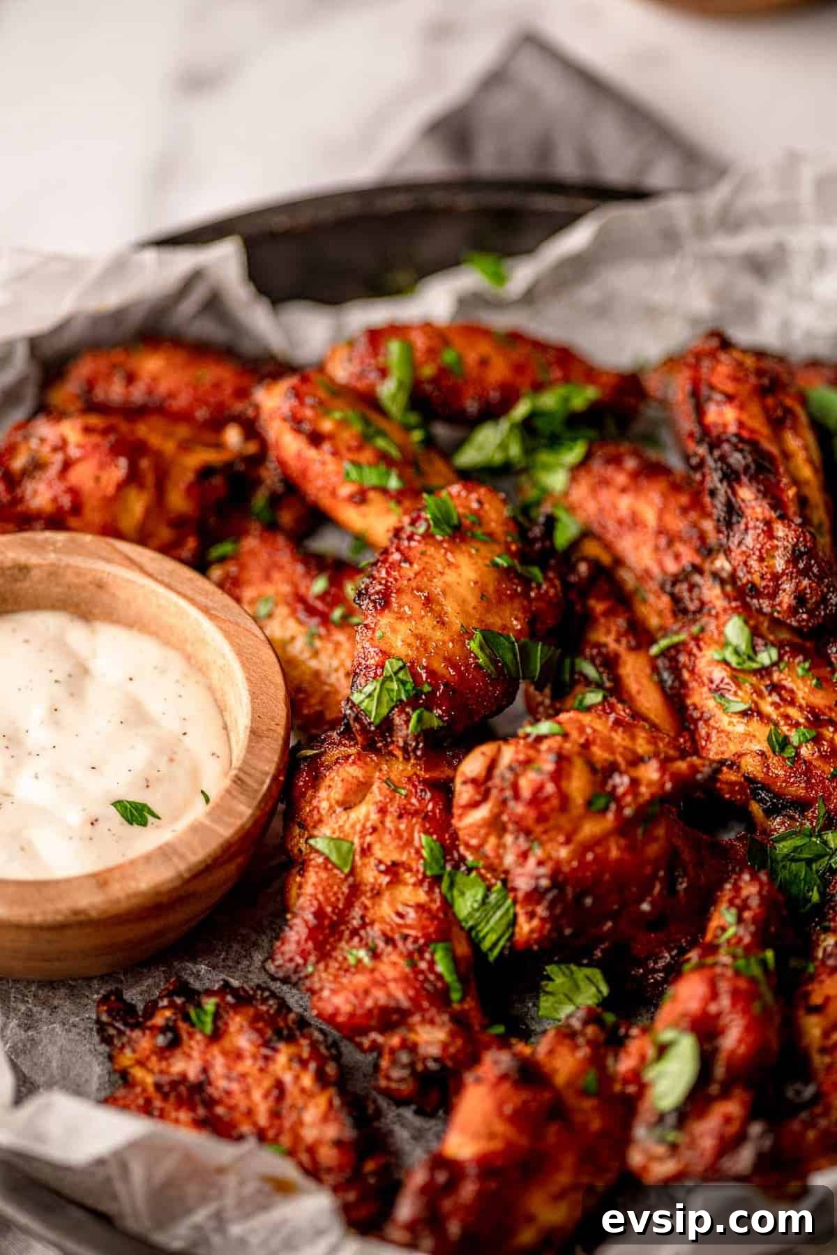 Wings next to a wooden bowl of blue cheese.