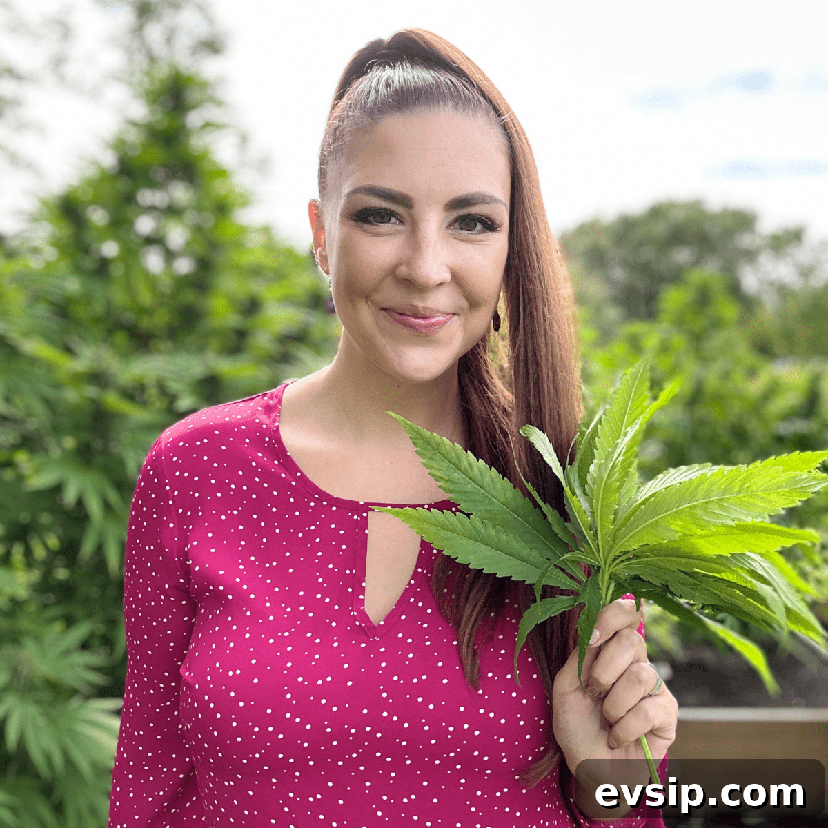 Cannabis Trichomes Explained: How They Affect Potency and Flavor 23 A picture of Emily Kyle in a cannabis garden holding cannabis fan leaves to be used for edibles.