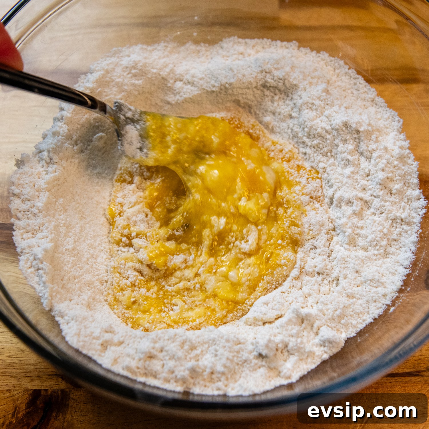 Egg being added to flour.