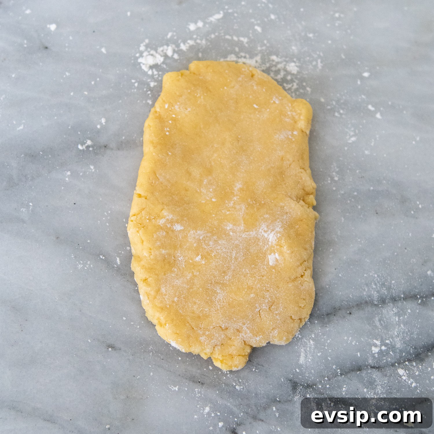 Pasta dough sprinkled with flour on a marble surface.