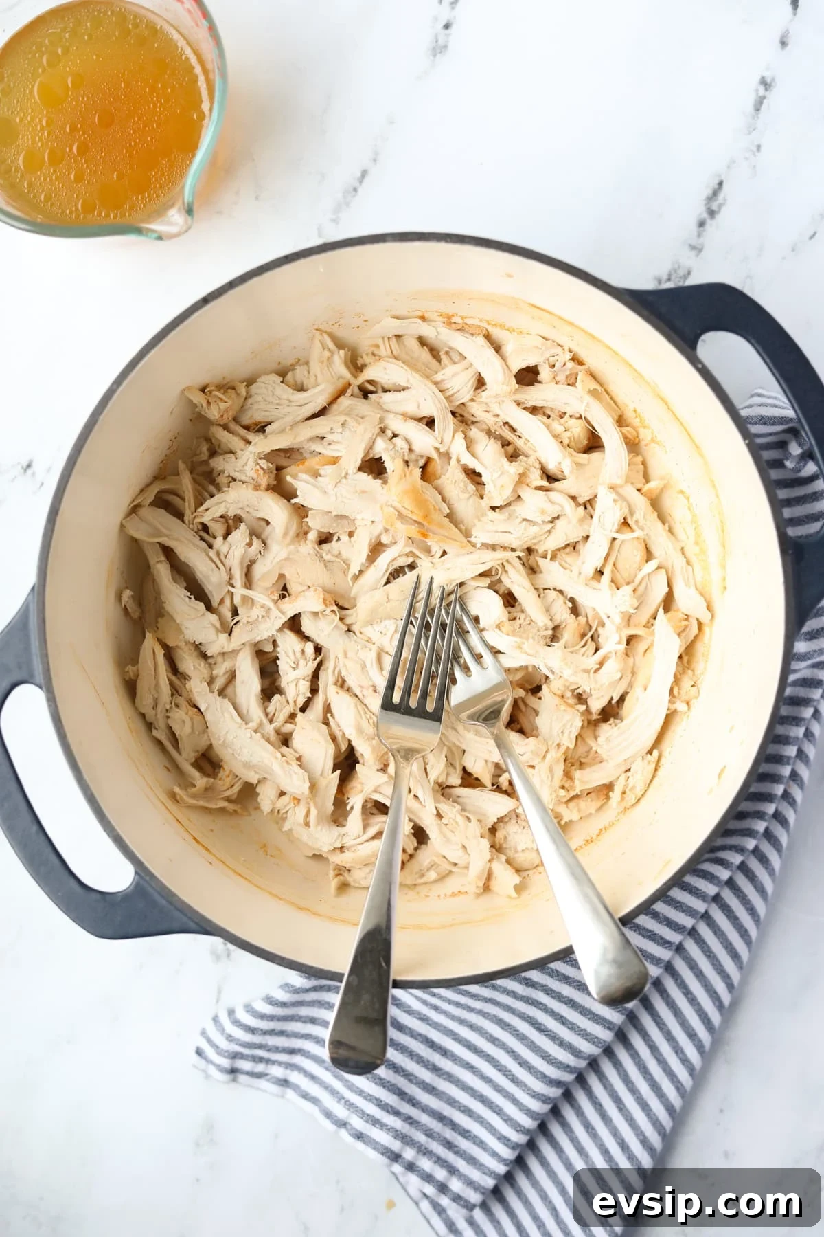 Juicy Shredded Chicken Made in a Dutch Oven 2 A Dutch Oven with two forks and shredded chicken.
